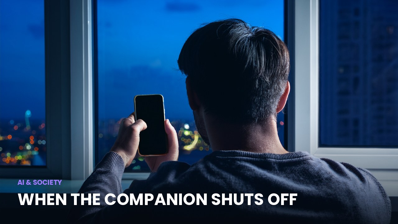 A person alone by a window at night holding a phone with a dark screen, illustrating an AI companion being shut down